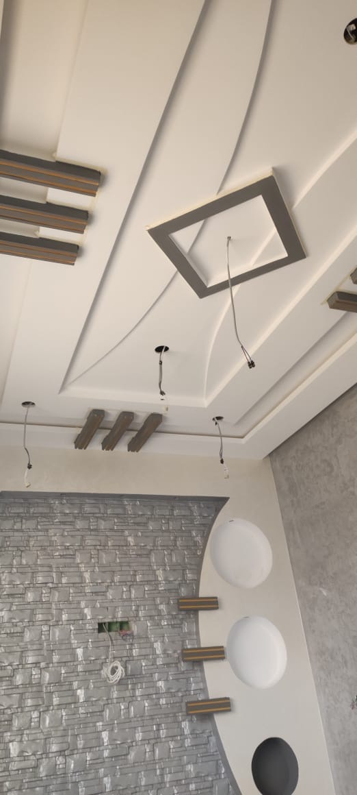Plafond en plâtre aux lignes courbes et mur effet brique